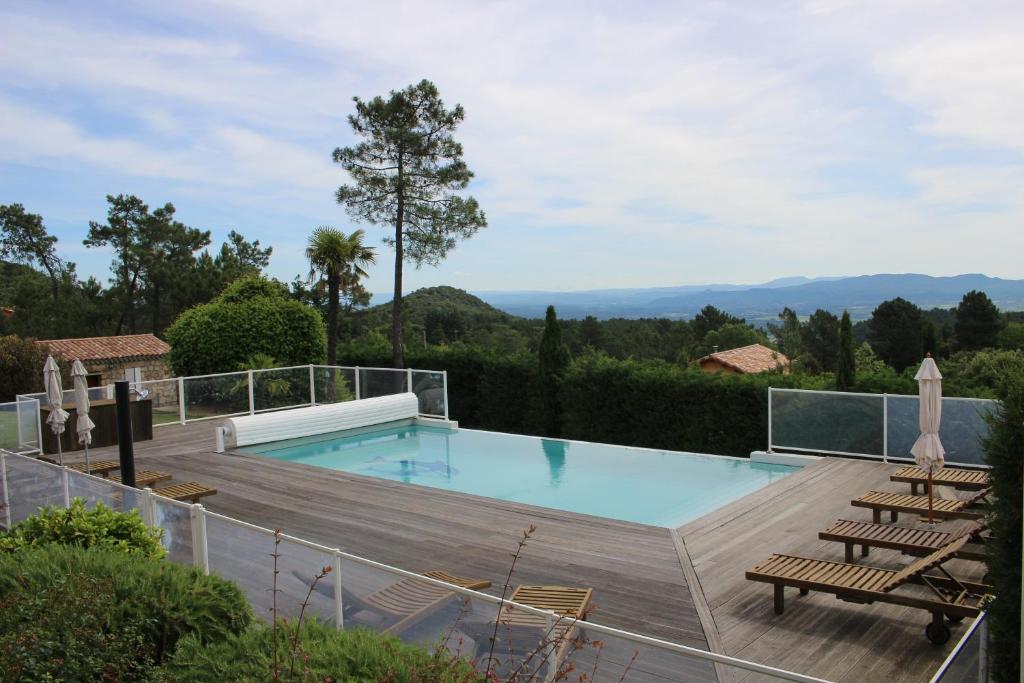 uma piscina com um deque e cadeiras de madeira em Les Clèdes du Mazel em Banne