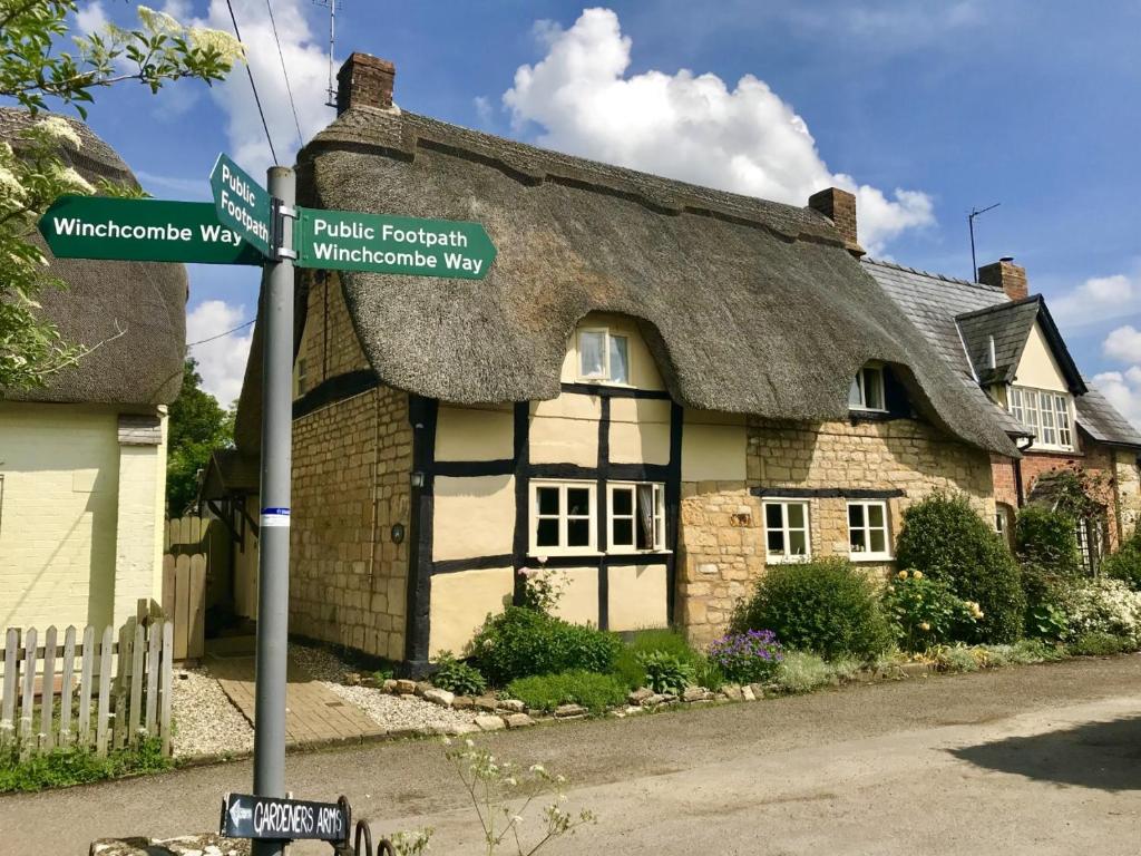 a thatched cottage with a street sign in front of it at Bells Cottage in Alderton
