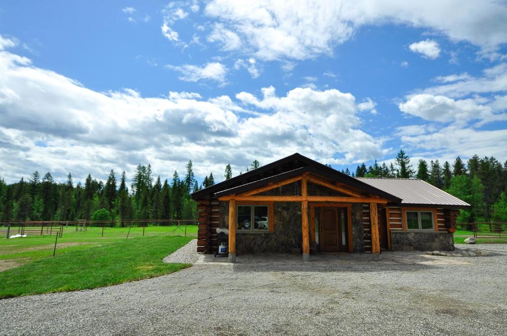 a small log cabin with a field and trees at Glacier Homestead in Coram