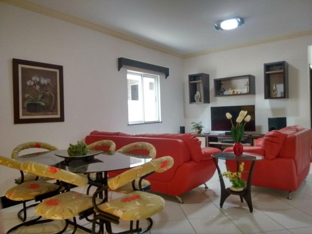 sala de estar con sofá rojo, mesa y sillas en Apartamento Luxo Cabo Frio, en Cabo Frío