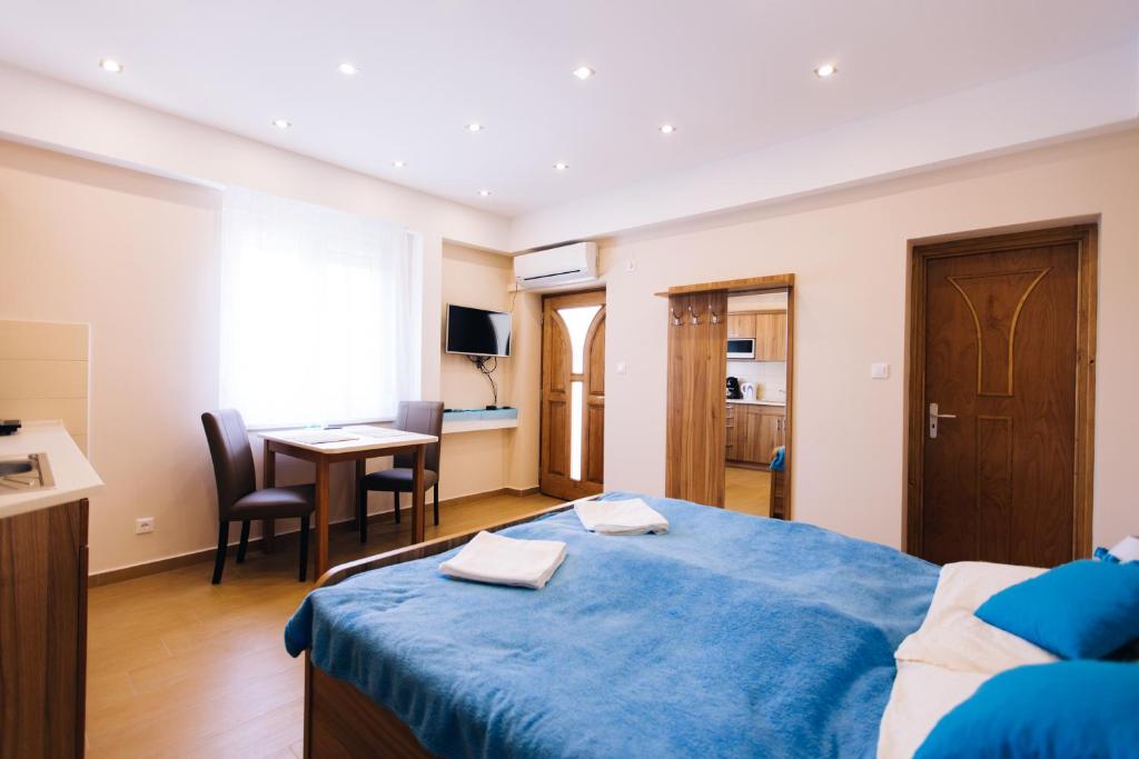 Schlafzimmer mit einem blauen Bett und einem Schreibtisch in der Unterkunft Lak6 Apartment in Mórahalom