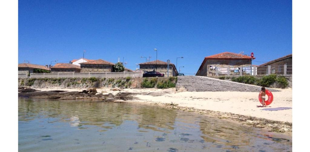 Virxe das Mareas的住宿－Casa de Playa Pet Friendly，站在海滩上的人,有冲浪板