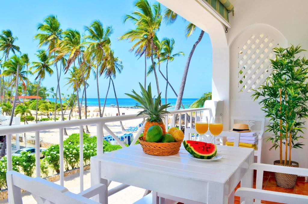 una mesa con fruta y zumo en un balcón con vistas a la playa en Beach Villas & Apartments Larimar, en Punta Cana