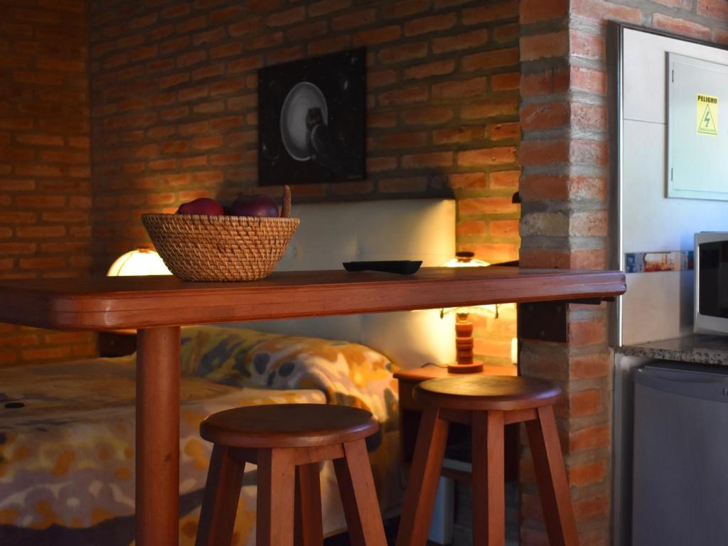 a table with two stools and a bowl of apples on it at Cabañas Latitud 38.15 in Sierra de la Ventana