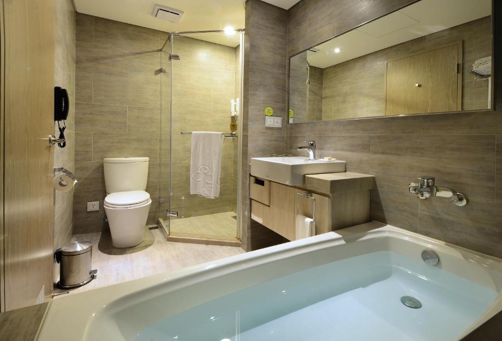 a bathroom with a tub and a toilet and a sink at Park City Hotel - Luzhou Taipei in Taipei