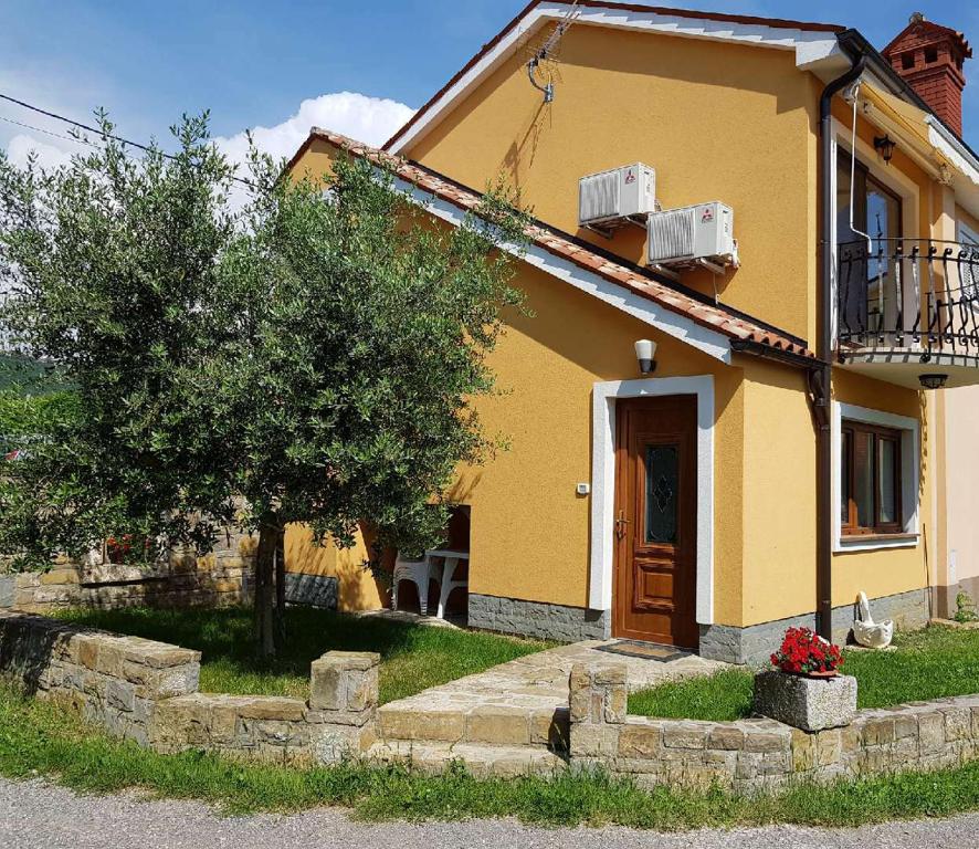 Una casa amarilla con un árbol delante. en Apartment between the vineyard, en Ankaran