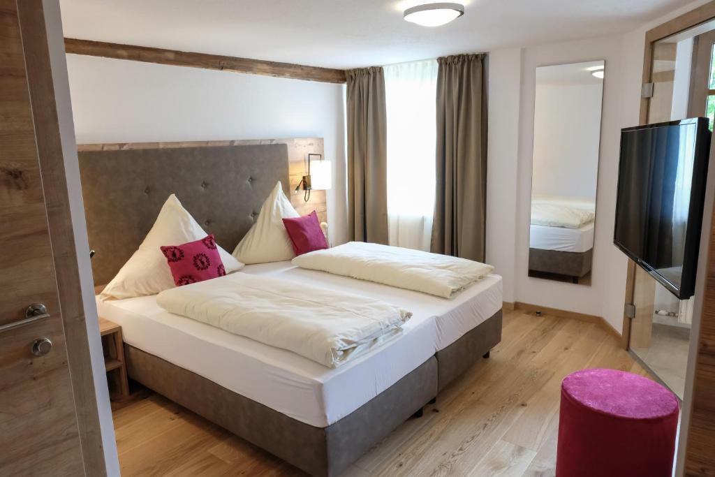 a hotel room with a bed and a flat screen tv at Alpengasthof zur Post in Schattwald