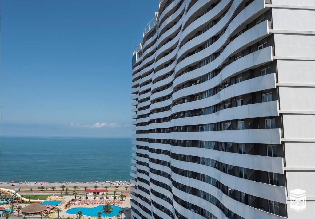 un edificio alto con el océano en el fondo en Orbi Residence Duplex Apartment en Batumi