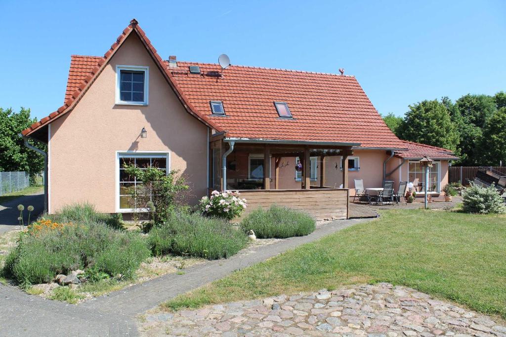 uma casa com um telhado vermelho e um quintal em Landhaus Peene em Sophienhof