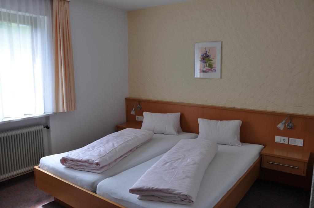 a bedroom with two beds with white sheets and a window at Haus Berchtold in Alberschwende