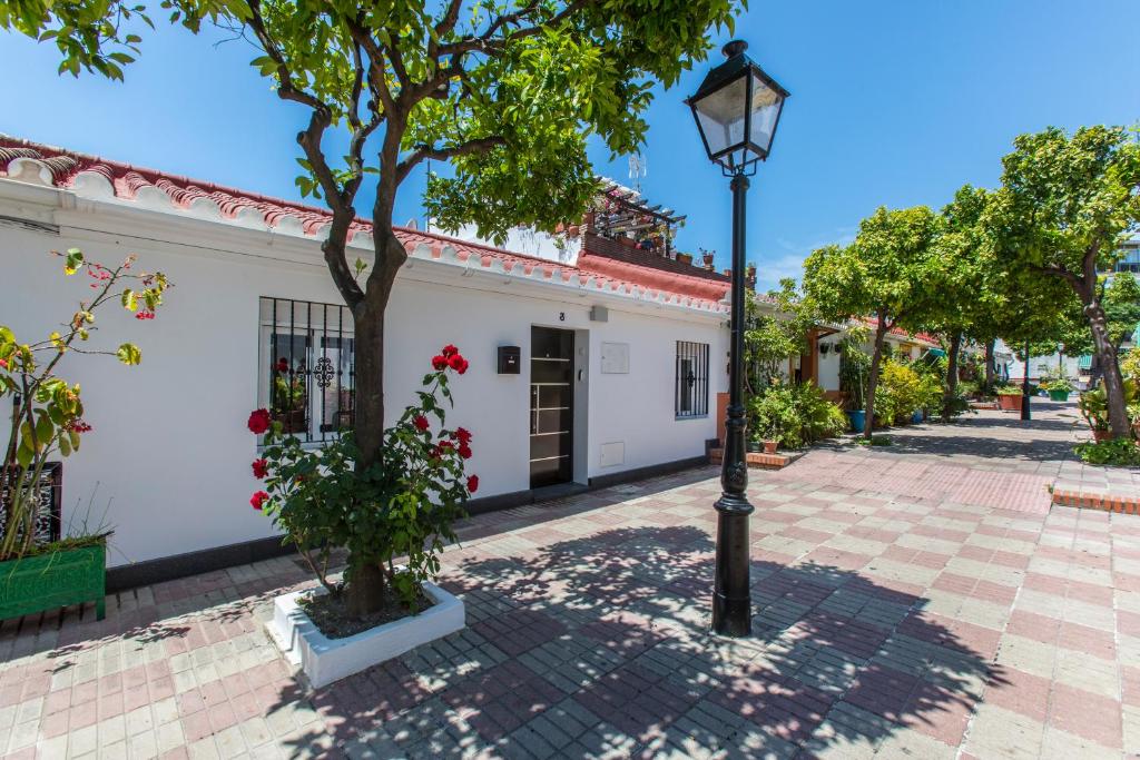 een straatlicht naast een wit gebouw met een boom bij Casa Alma in Marbella