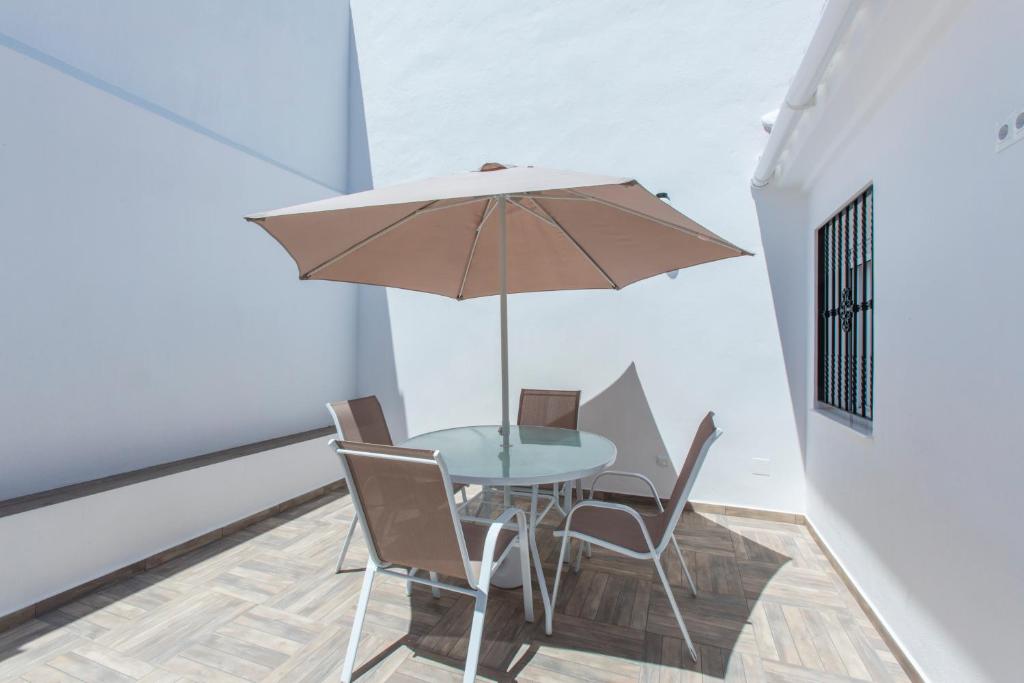 a glass table with chairs and an umbrella at Casa Alma in Marbella