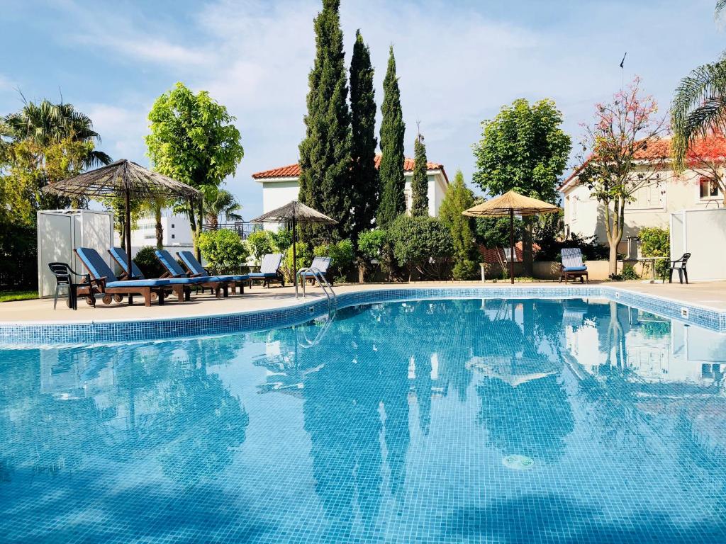 una grande piscina con sedie e ombrelloni di Leto beach house a Limassol