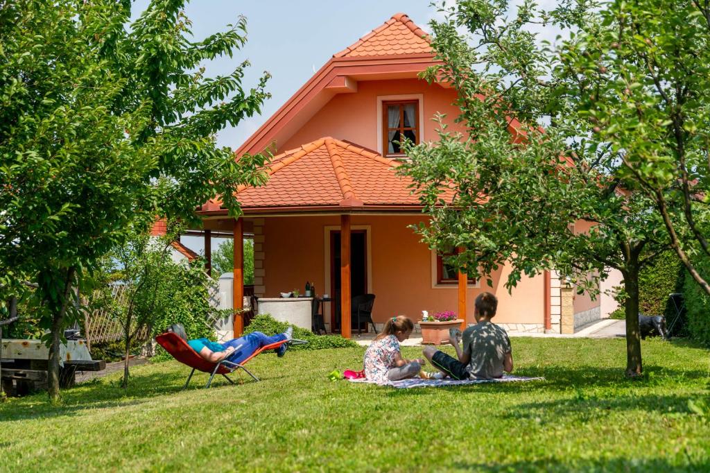 two children sitting in the grass in front of a house at PLANINCA -hiša z razgledom in Šmarje pri Jelšah