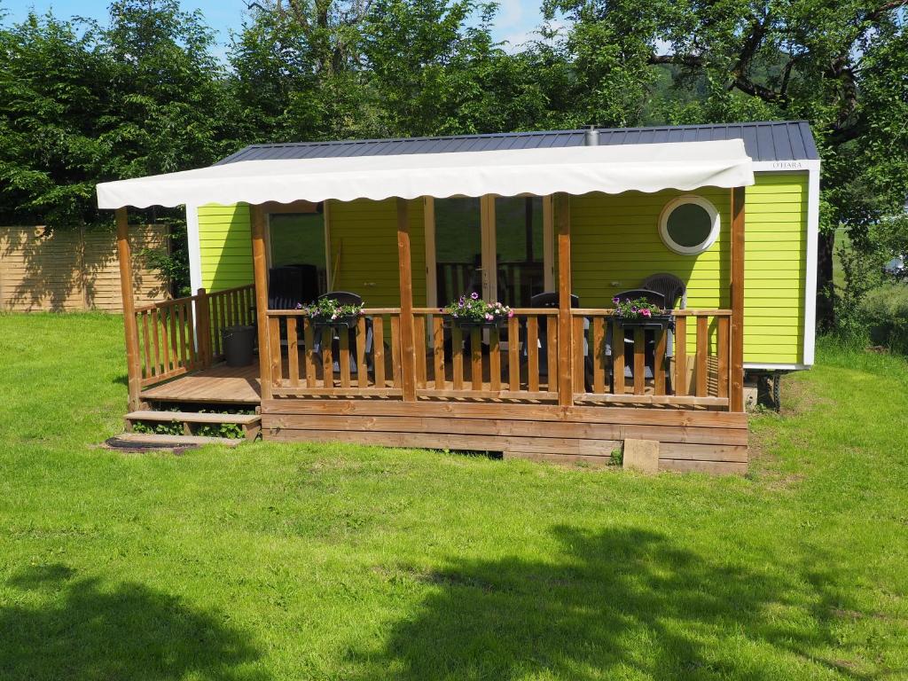 una casa verde con una terraza con 2 sillas en Camping Rocher De La Vierge, en Comblain-la-Tour