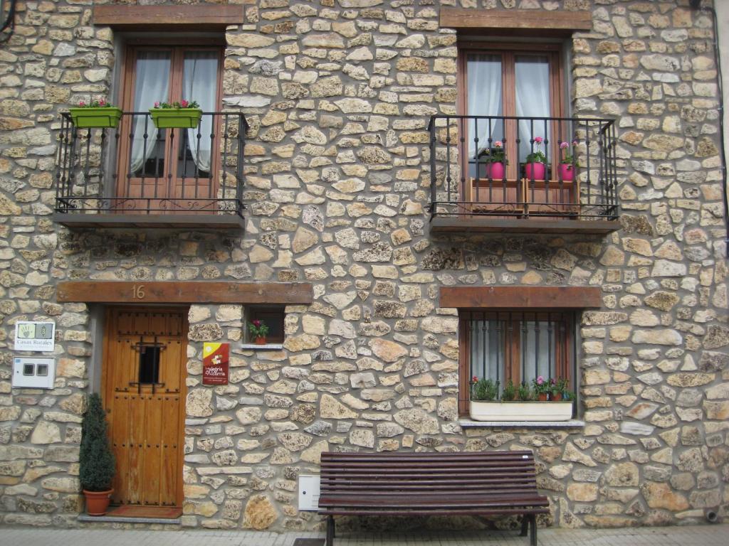 een stenen gebouw met drie ramen en een bank bij Casa La Alegría de La Alcarria I in Torremocha del Campo