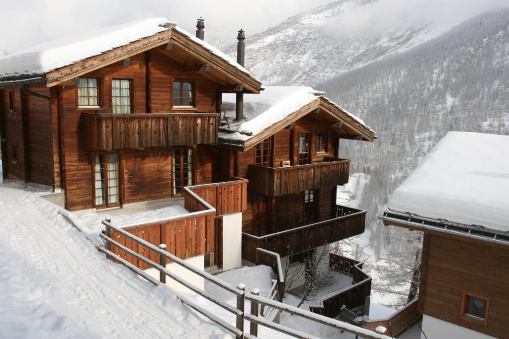 una cabaña de madera en la nieve con nieve en Mountain Village 11, en Saas-Fee