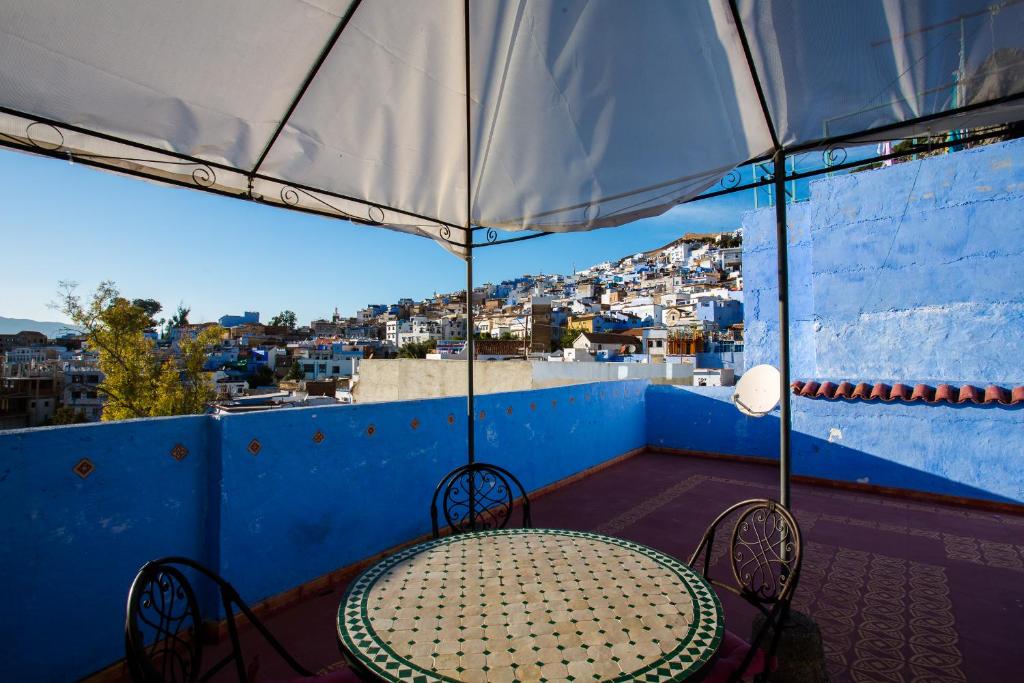 d'une table et de chaises sur un balcon avec un parasol dans l'établissement Dar Carlos, à Chefchaouen