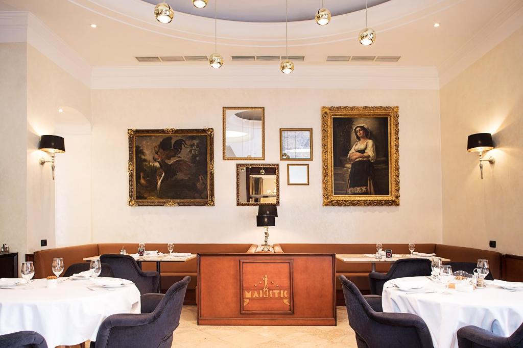 a dining room with tables and chairs and portraits on the wall at Hotel Majestic in Belgrade