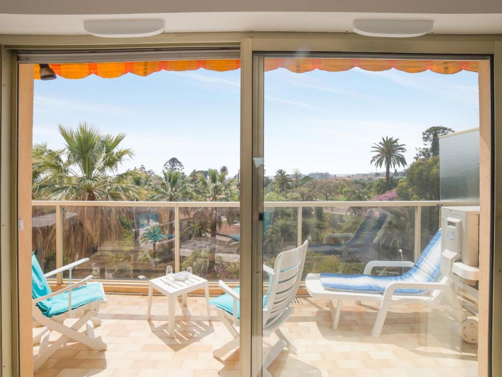 a balcony with a view of the ocean and palm trees at Welkeys - Fabron Apartment in Nice
