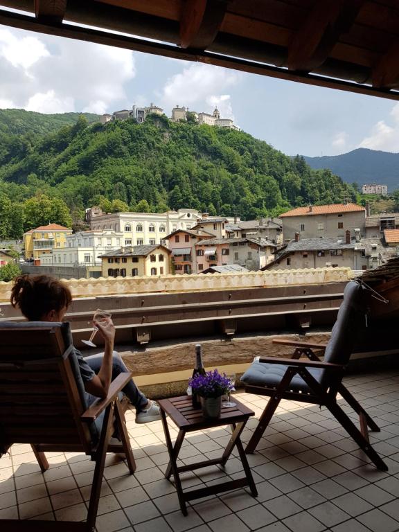 kobieta siedząca na krześle na balkonie patrząca na miasto w obiekcie Attico sul Fiume w mieście Varallo