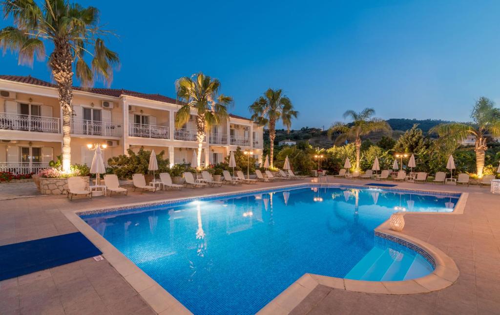 a swimming pool in front of a hotel at night at Edelweiss Hotel in Argassi