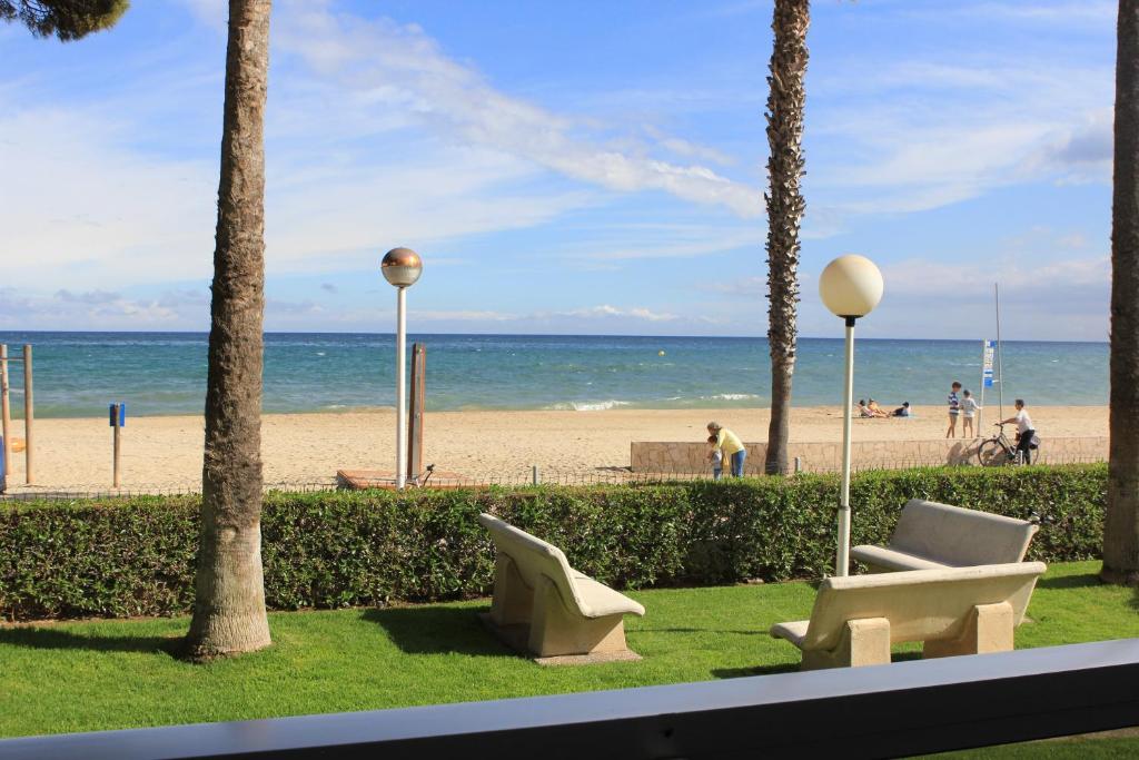 a view of a beach with palm trees and a chair at Playa Esquirol in Cambrils