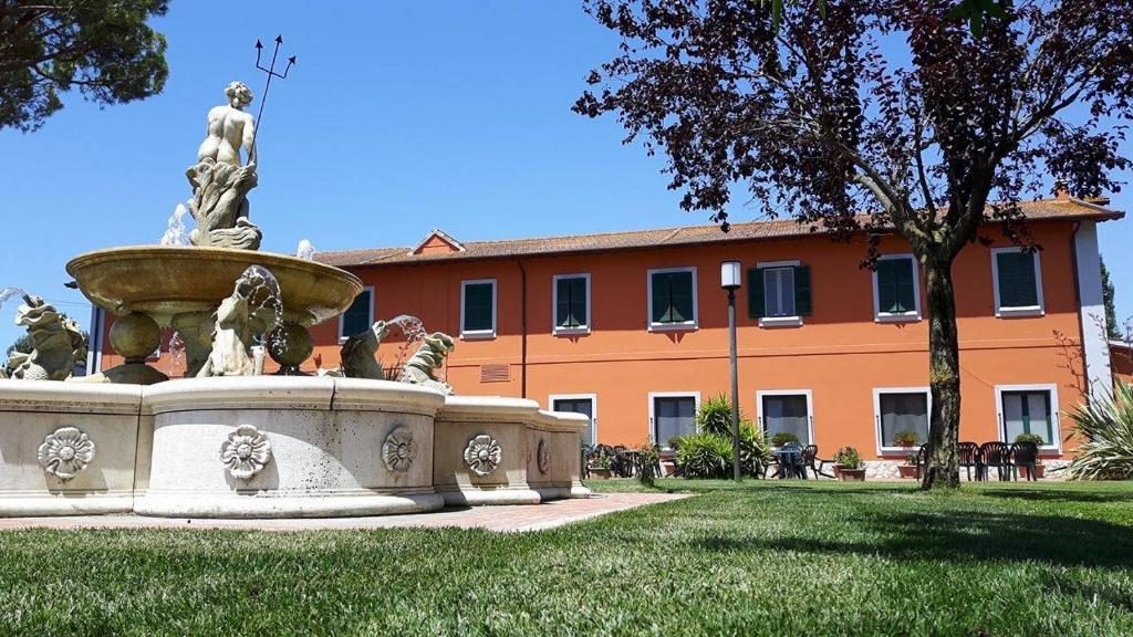 a fountain in the grass in front of a building at Il Casale Corte Rossa in Latina