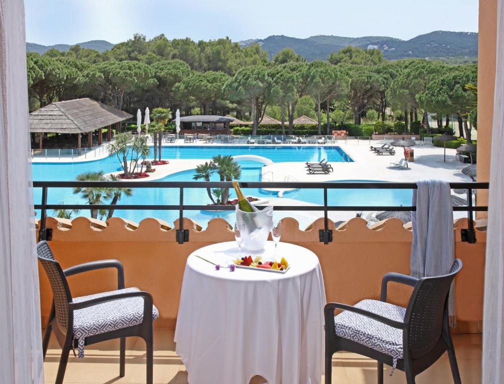 a balcony with a table and chairs and a pool at La Costa Hotel Golf & Beach Resort in Pals