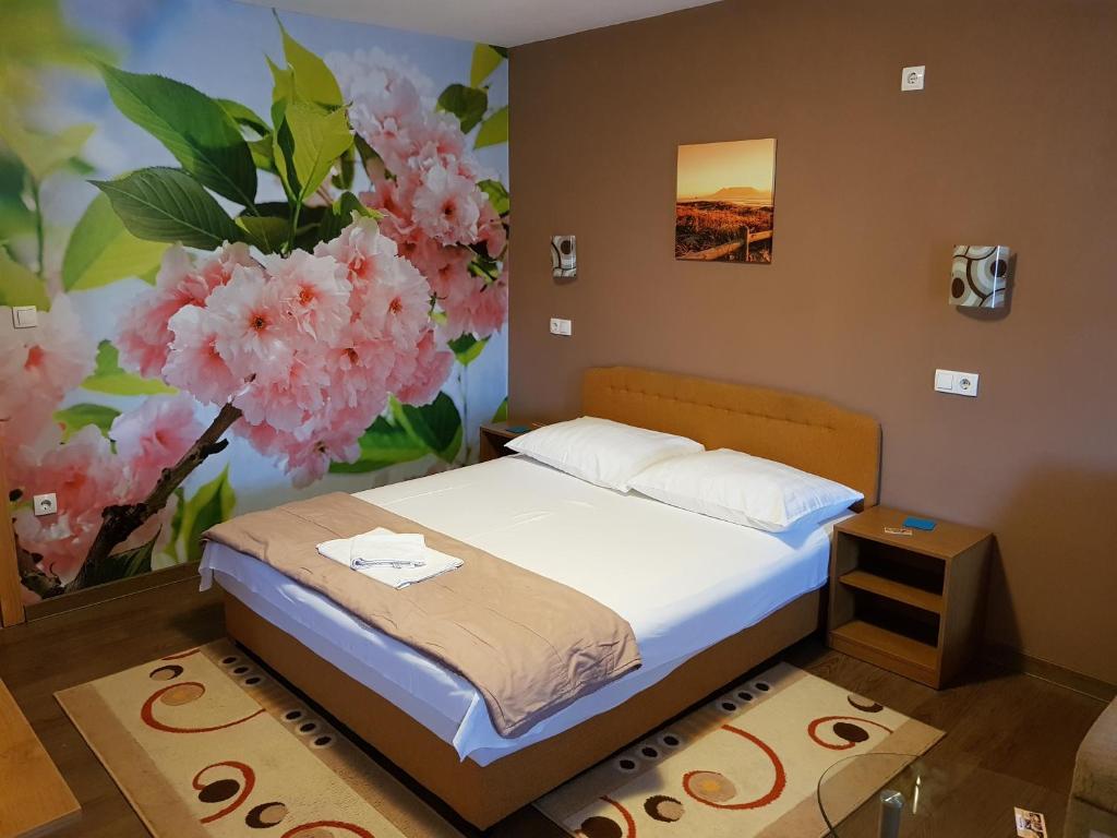 um quarto com uma cama e um mural de flores em Guest House Babilon em Prijedor