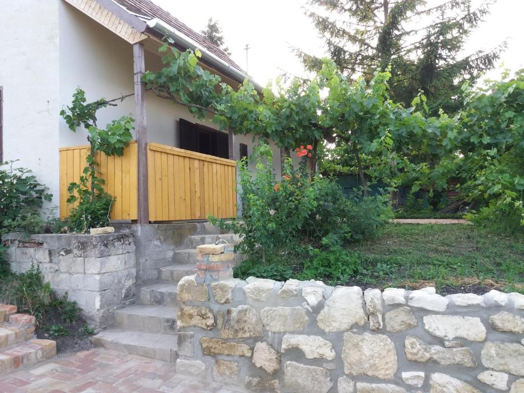 a house with a stone retaining wall and a fence at Bella Vendégház in Etyek