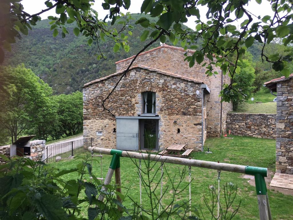 Pardines的住宿－Cal Sastre，一座古老的石头建筑,在田野上有一扇门