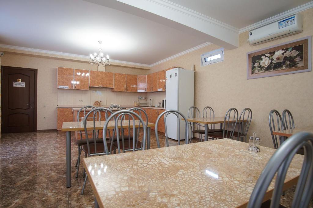a kitchen with tables and chairs and a refrigerator at Anita Guest House in Adler