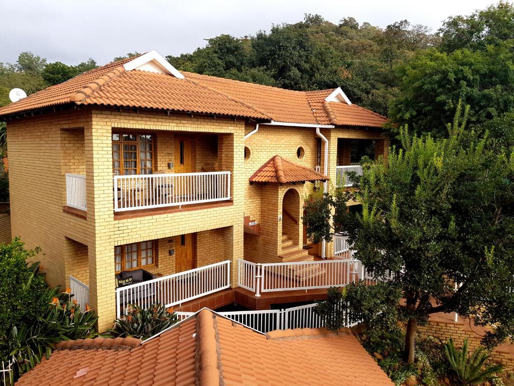 a large house with a balcony and trees at Boschdal Upmarket Guesthouse in Rustenburg