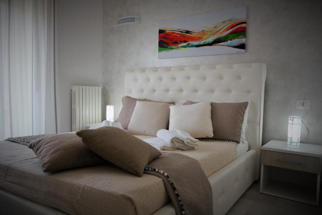 - une chambre avec un grand lit blanc et une tête de lit blanche dans l'établissement Central Apartments, à Crotone