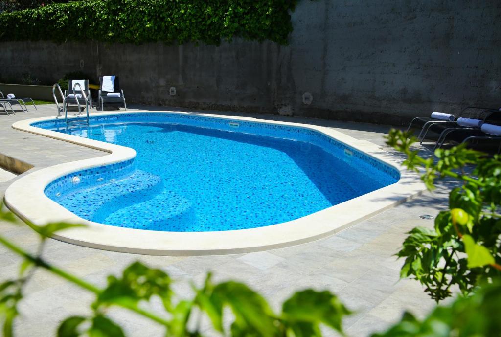 a swimming pool in a yard with chairs around it at Apartments Nemira Exclusive in Omiš