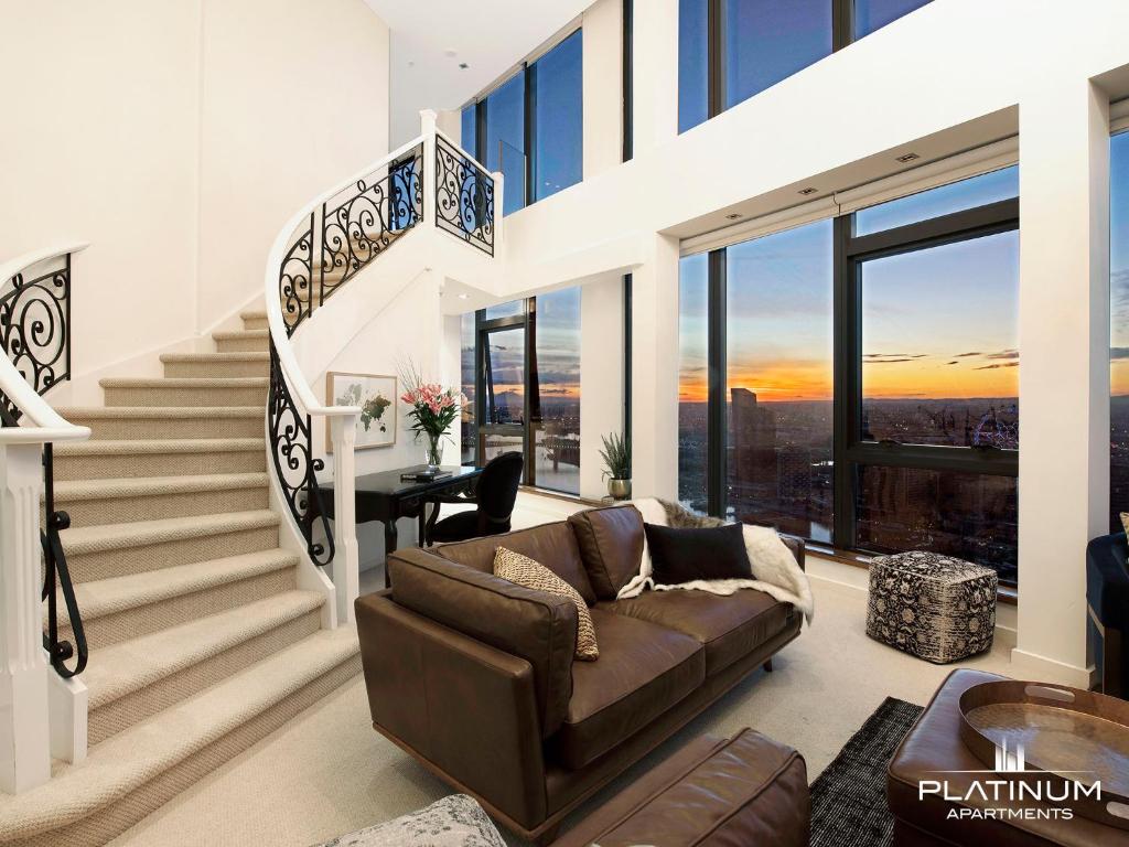 a living room with a couch and a staircase at Platinum Luxury Stays at The Victoria Rooftop Penthouse in Melbourne