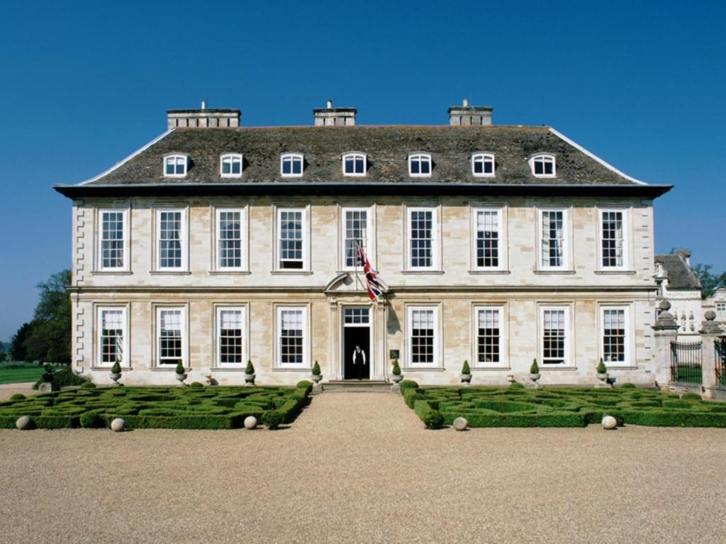 Um grande edifício com uma bandeira americana à frente. em Stapleford Park Hotel & Spa em Melton Mowbray