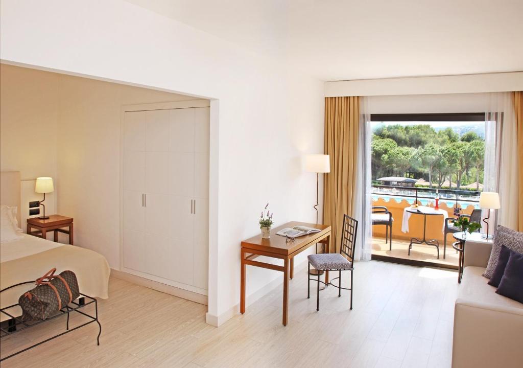 a hotel room with a bed and a table and chairs at La Costa Hotel Golf & Beach Resort in Pals