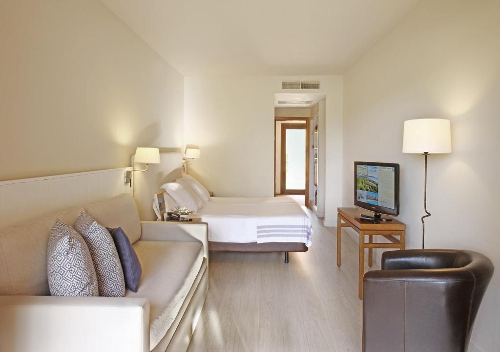 a hotel room with a bed and a couch at La Costa Hotel Golf & Beach Resort in Pals