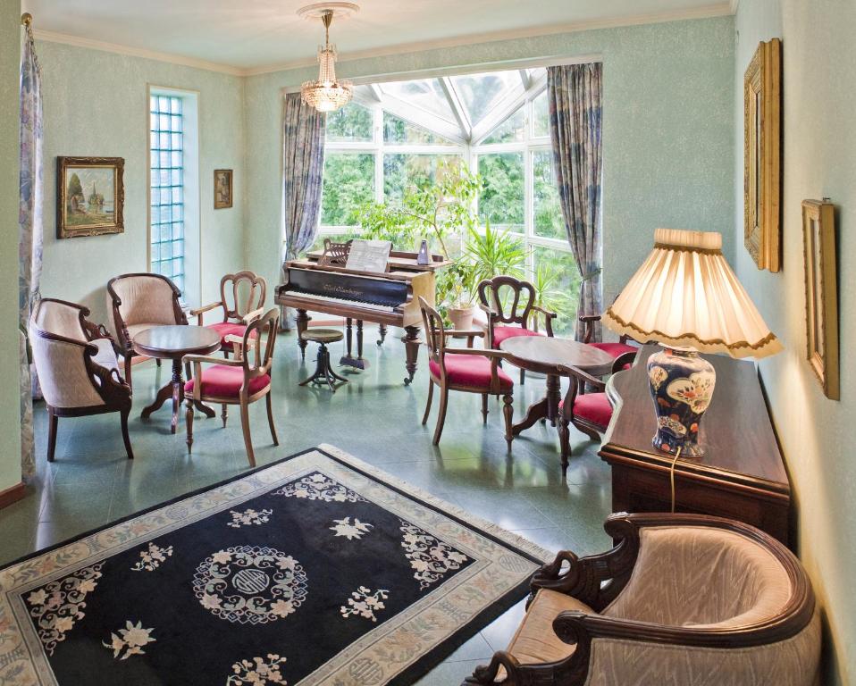 - un salon avec une table, des chaises et un piano dans l'établissement Hotel Panzió Nr100 Aparthotel konyha nélkül, à Szentendre