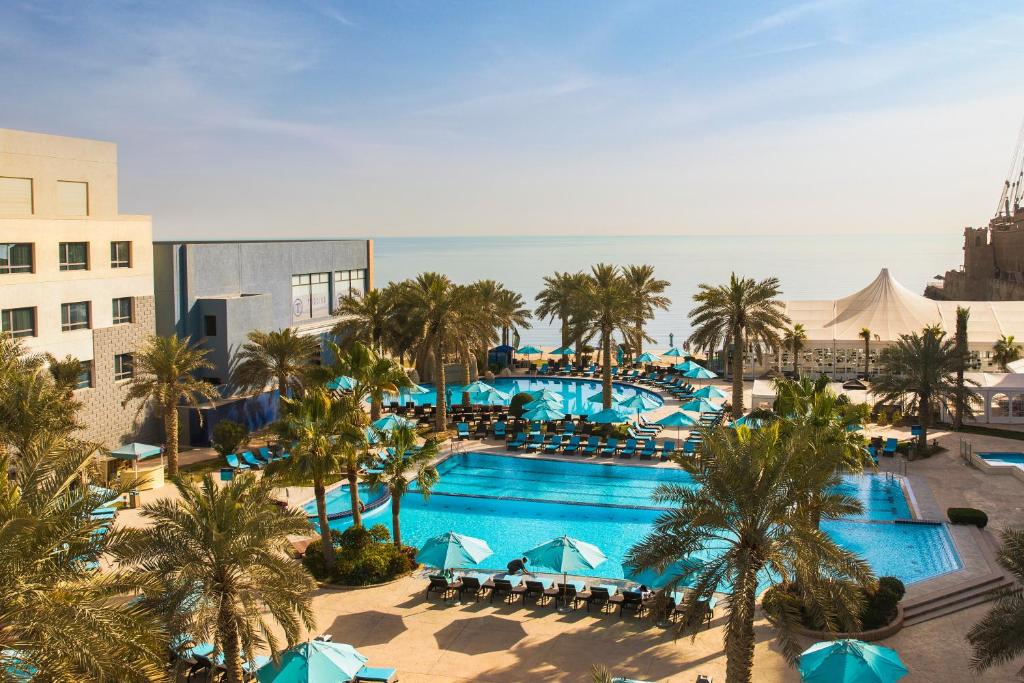 uma vista aérea de uma piscina de resort com palmeiras em The Palms Beach Hotel & Spa em Kuwait