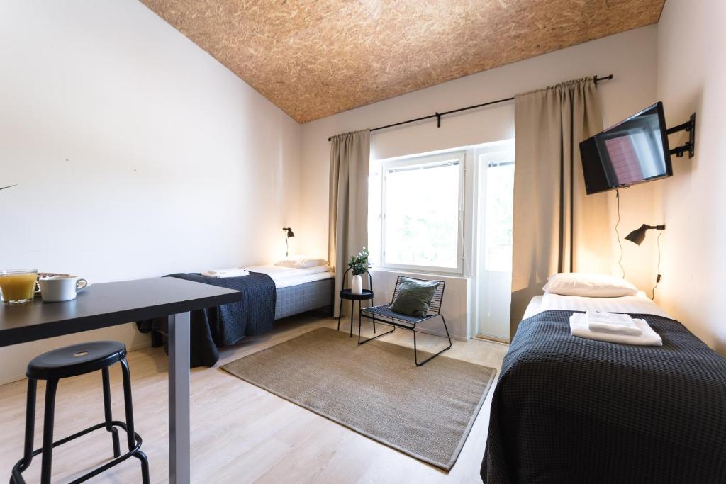 Cette chambre comprend deux lits, un bureau et une fenêtre. dans l'établissement Spot Apartments Uusmäki, à Espoo