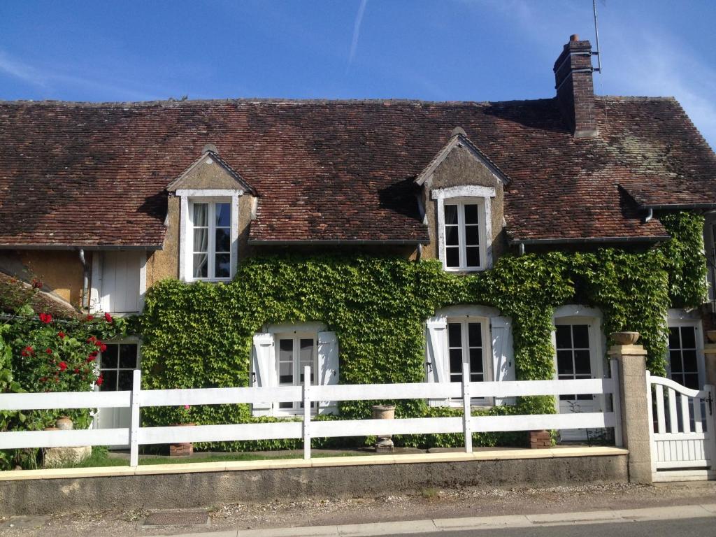a white fence in front of a house with ivy at La Vigne dorée in Saint-Martin-des-Champs