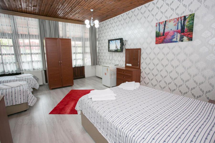 a bedroom with two beds and a red rug at Çarşı butik otel in Amasra