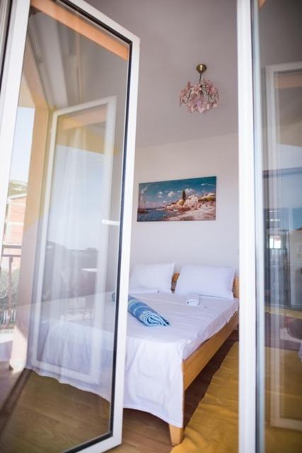 a mirror next to a bed in a room at Apartmani Šutić in Promajna