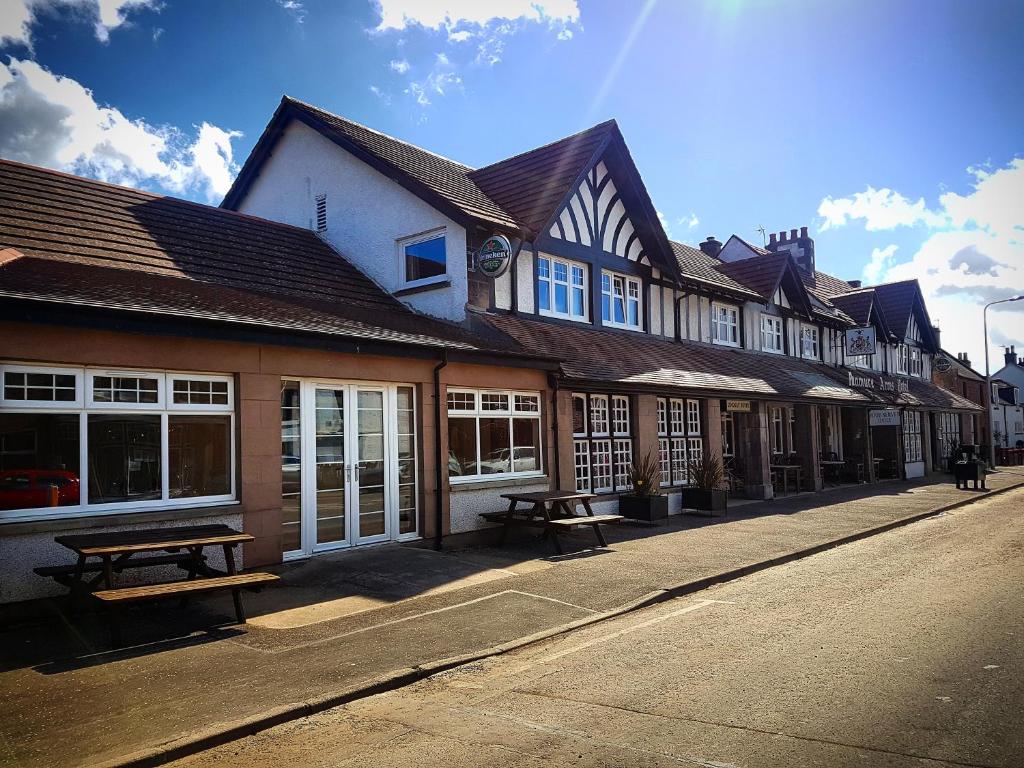 a row of buildings with benches on a street at The Panmure Arms Hotel in Edzell