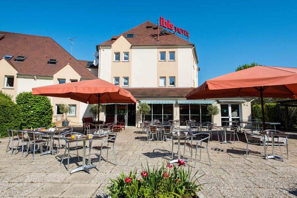 une terrasse avec des tables et des parasols en face d'un hôtel dans l'établissement Ibis Château-Thierry, à Essômes-sur-Marne