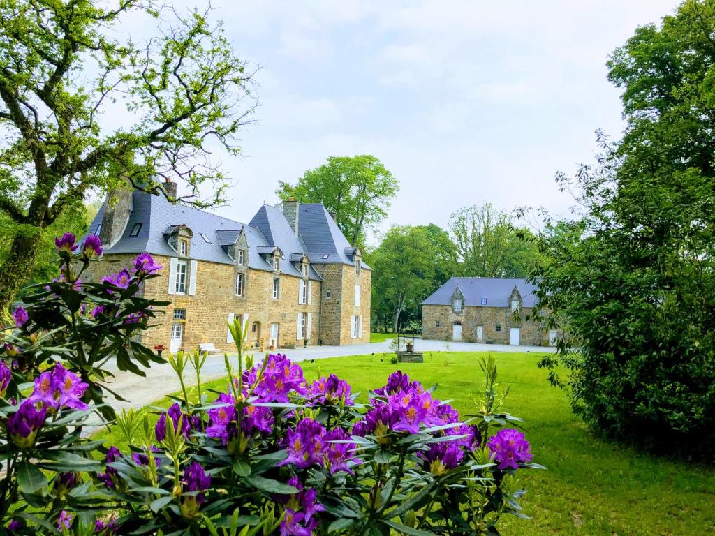 una casa grande con flores púrpuras delante de ella en Chambres d'hôtes Château de La Croix Chemin, en Saint-Léger-des-Prés