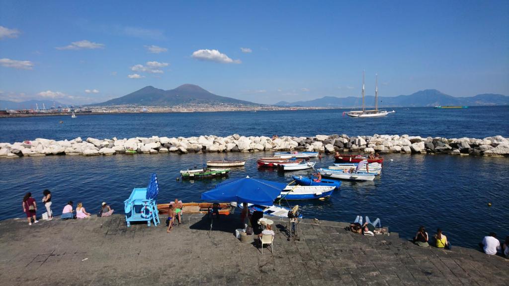 un grupo de personas en una playa con barcos en el agua en Parthenope's Nest, en Nápoles